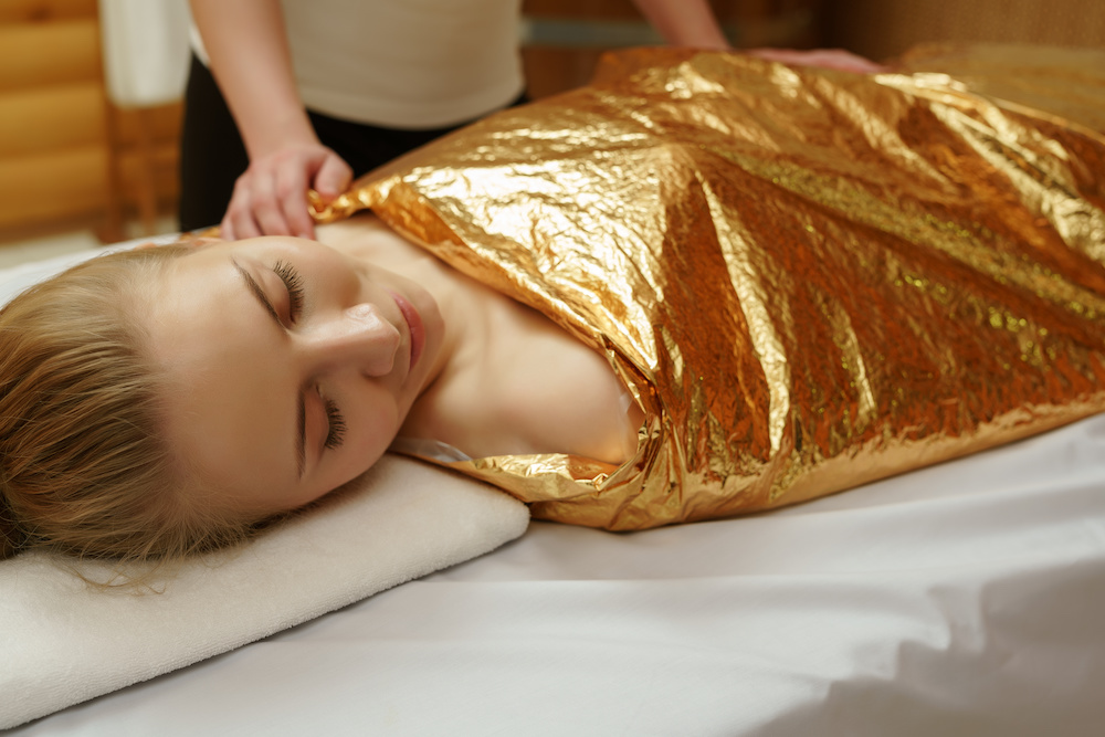Woman laying on table wrapped in spa body wrap
