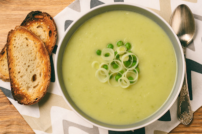 potato leek soup in a bowl with toasted bread and spoon
